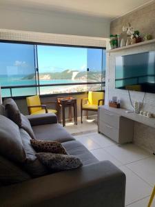 een woonkamer met een bank en uitzicht op de oceaan bij Duas suítes com a melhor vista de Ponta Negra! in Natal