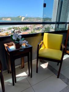 een gele stoel en een tafel op een balkon bij Duas suítes com a melhor vista de Ponta Negra! in Natal
