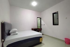 una piccola camera con letto e specchio di OYO 93175 Wisma Syariah Dian a Barru