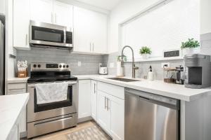 eine Küche mit weißen Schränken und Küchengeräten aus Edelstahl in der Unterkunft Ballard Home Base - Comfy Modern House in Seattle in Seattle