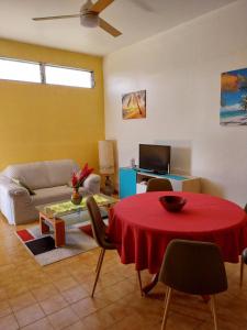 a living room with a red table and a couch at BIENVENUE AU SOLEIL LEVANT assier entrée morne savon ,le lorrain in Le Lorrain