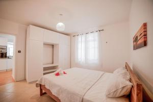 a white bedroom with a bed with flowers on it at Maison à 5 mins de la plage et des commerces in Flic-en-Flac