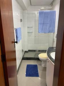 La salle de bains est pourvue de toilettes, d'un lavabo et de serviettes bleues. dans l'établissement APARTAMENTO SOL E MAR VITÓRIA, à Vitória