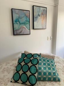 duas fotos na parede acima de uma cama com duas almofadas em APARTAMENTO SOL E MAR VITÓRIA em Vitória