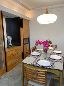 a dining room table with plates and flowers on it at APARTAMENTO SOL E MAR VITÓRIA in Vitória