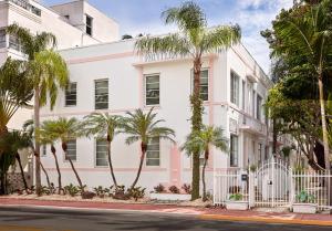 a white building with palm trees in front of a street at Pantera Rosa in Miami Beach