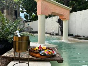 a plate of food sitting on a table next to a swimming pool at Historic House Hotel boutique in Mérida +64 photos
