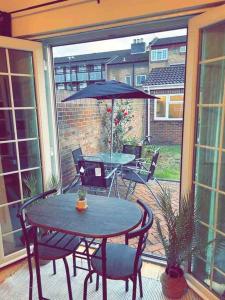 une terrasse avec une table, des chaises et un parasol dans l'établissement 7 BR Town House, Kingsize Beds, Free Parking, à Slough