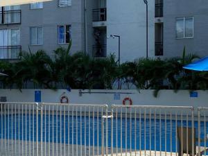 una piscina azul frente a un edificio en Lindo apto 2 habitaciones cerca al Aeropuerto Y centro de Eventos valle del pacifico 