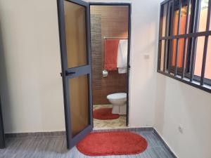 a bathroom with a toilet and a red rug at Fafape in Lomé +16 photos
