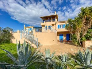 a large house with blue doors and a palm tree at Tapia Hills in Methoni