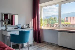 シュクラルスカ・ポレンバにあるWilla Sonata - w otoczeniu natury z widokiem na góryのデスク、窓、青い椅子が備わる客室です。