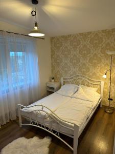 a white bed in a bedroom with a window at Ditemo center apartment self check in in Šiauliai