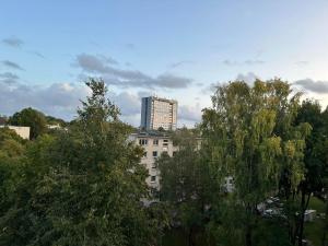 a tall building in the distance behind some trees at Ditemo center apartment self check in in Šiauliai