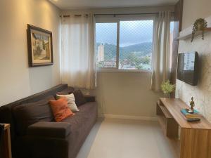 a living room with a brown couch and a window at House Park completo em Blumenau-SC in Blumenau