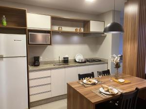 a kitchen with a table and a white refrigerator at House Park completo em Blumenau-SC in Blumenau