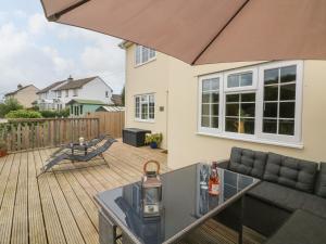 a patio with a couch and a table on a deck at Sunny Views in Ilfracombe