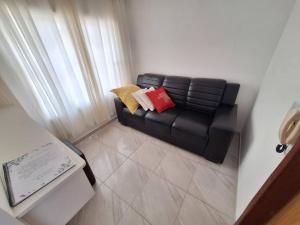 a black leather couch with two pillows in a room at Apartamento Venda Nova do Imigrante in Venda Nova do Imigrante