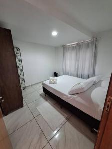 una camera da letto con un letto con lenzuola e cuscini bianchi di Apartamento "Lavanda" - Venda Nova do Imigrante a Venda Nova do Imigrante
