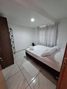 - une chambre avec un lit doté de draps et d'oreillers blancs dans l'établissement Apartamento Venda Nova do Imigrante, à Venda Nova do Imigrante
