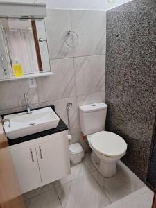 La salle de bains est pourvue de toilettes blanches et d'un lavabo. dans l'établissement Apartamento Venda Nova do Imigrante, à Venda Nova do Imigrante