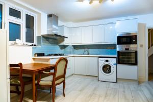 a kitchen with white cabinets and a table and a washing machine at Alpha Grove in London