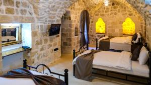 a bedroom with three beds in a stone room at AĞA KONAĞI HOTEL in Mardin