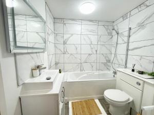 a white bathroom with a tub and a toilet and a sink at 2 Bed Luxury Apt in Gravesend in Kent