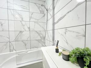 a bathroom with white marble walls and a tub at 2 Bed Luxury Apt in Gravesend in Kent