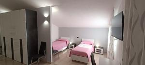 2 posti letto in una piccola stanza con lenzuola rosa di LA CASA DI ROBERTO a Madonna della Pace