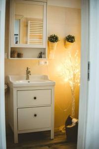 ein Badezimmer mit einem Waschbecken, einem Spiegel und einem Baum in der Unterkunft Byt pod ateliérom 