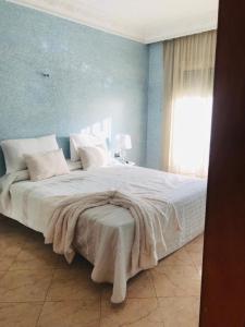 a bedroom with a large white bed with a blue wall at Apartamento hay amal 12 in Salé
