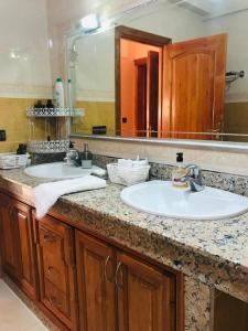 a bathroom with two sinks and a large mirror at Apartamento hay amal 12 in Salé