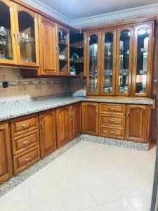 a kitchen with wooden cabinets and marble counter tops at Apartamento hay amal 12 in Salé