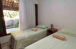 two beds in a room with a window at RCM Vilas - Casa das redes in Barra Velha