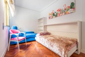 een slaapkamer met een bed en een stoel bij Bonita habitación con balcón in Villaviciosa de Odón