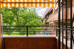 a balcony with an awning and a tree at Bonita habitación con balcón in Villaviciosa de Odón