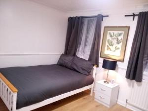 a bedroom with a bed and a lamp on a night stand at Big spacious 4 Bed House Romford London in Harold Wood