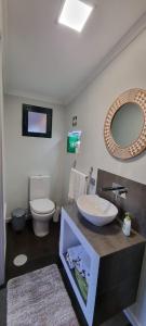 een badkamer met een wastafel, een toilet en een spiegel bij Studio em Machico in Machico