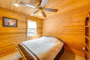 a bedroom with a ceiling fan in a log cabin at Lakefront Wisconsin Escape with Boat Dock and Kayaks! in Oconomowoc