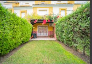 a house with a yard with a gate and bushes at Adosado en Islantilla in Islantilla