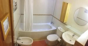 un bagno con vasca, WC e lavandino di Casa Volcan a Corralejo