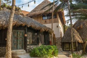 une maison avec des toits de chaume et des palmiers dans l'établissement Diamante K - Inside Tulum National Park, à Tulum