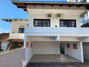 a white house with a balcony in front of it at RCM Vilas - Casa confortável 1 in Joinville