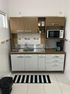 uma cozinha com um lavatório e um micro-ondas em RCM Vilas - Casa confortável 1 em Joinville