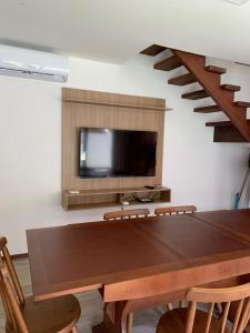 a dining room with a table and a tv and stairs at Apartamento de alto padrão no centro de Barra Grande in Barra Grande