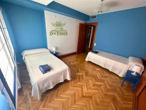 a room with two beds and a blue wall at Dos Torres Ático - Solárium Privado en Calle Alfonso I in Zaragoza