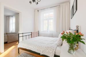 ein weißes Schlafzimmer mit einem Bett und einer Vase aus Blumen in der Unterkunft Apartament Nowe Miasto - przy Deptaku Chrobrego in Gorzów Wielkopolski