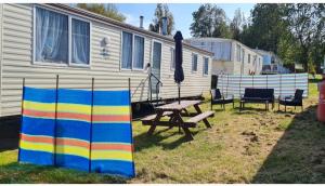 una mesa de picnic y una sombrilla frente a una casa en Warden spring en Leysdown-on-Sea