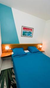 Un dormitorio con una cama azul y una foto en la pared en Le Colibri des Alizés, en Saint-François